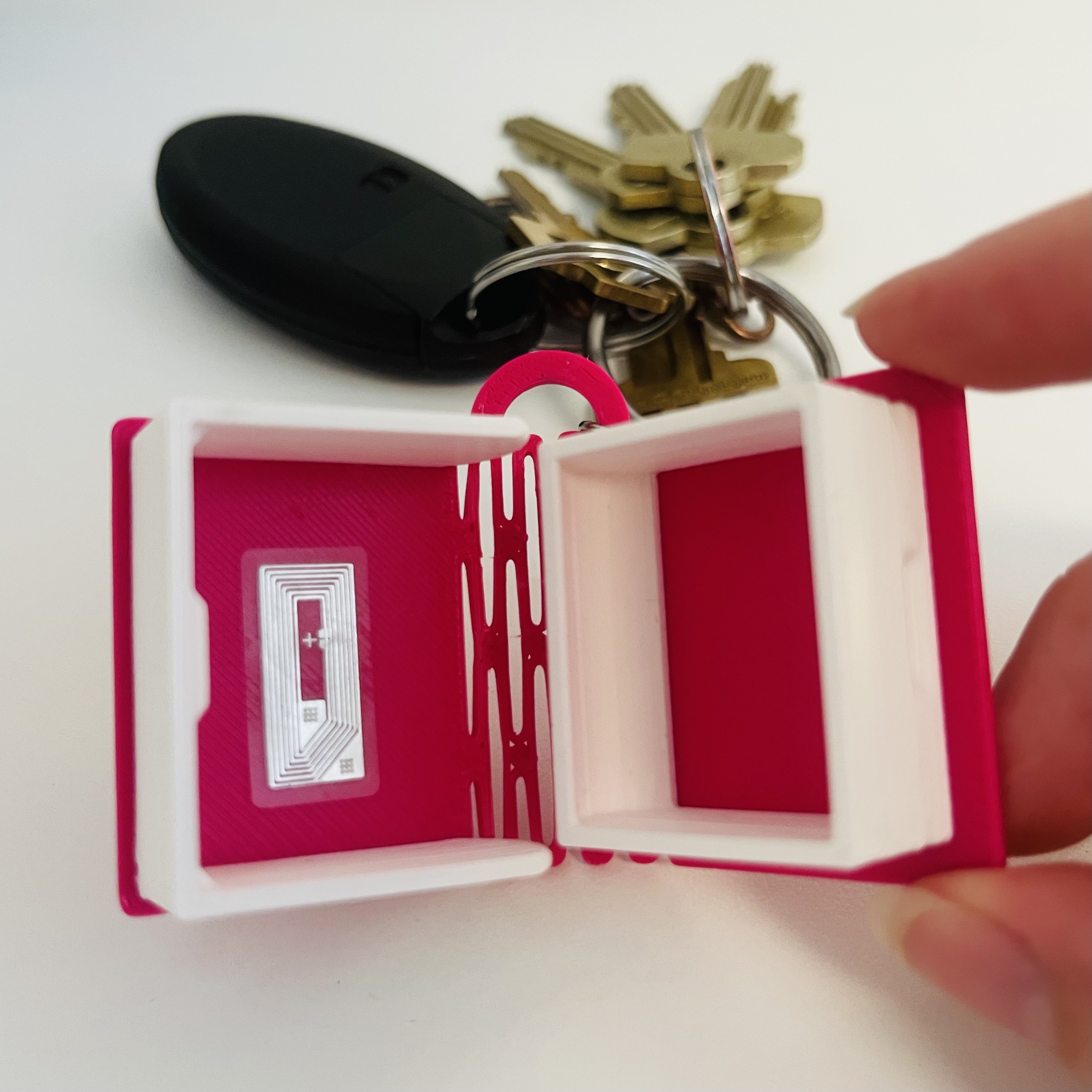 keychain of hot pink book with white pages and NFC tag inside